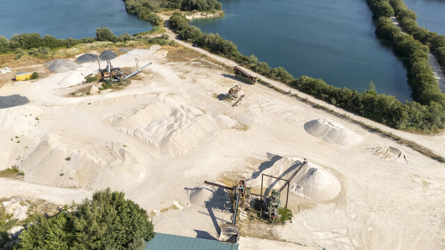 Aerial view of the Extraccion de aridos Lima S.L sand extraction site with machinery, conveyor belts, and piles of sand near water bodies in Vilarino das Poldras, Ourense, Spain.