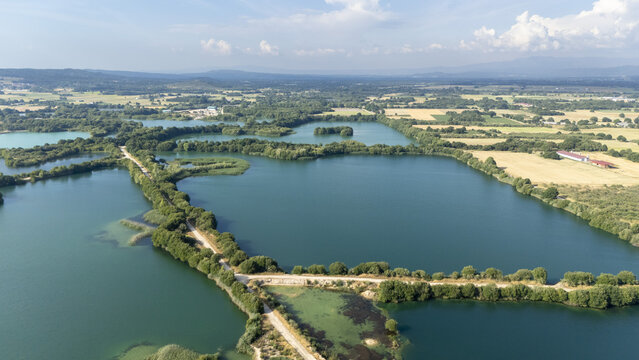 Aerial view of Areeiras da Limia featuring turquoise ponds surrounded by lush greenery, dirt paths, and agricultural fields in Ourense, Ourense, Spain.
