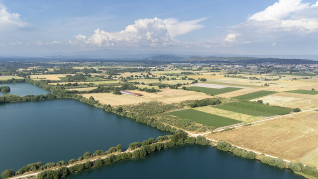 Aerial view of Areeiras da Limia featuring calm blue water reservoirs surrounded by agricultural fields, green trees, and distant hills in Ourense, Ourense, Spain.