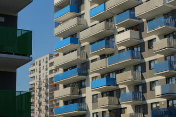 Modern apartment buildings with colorful balconies under a clear blue sky, showcasing contemporary residential architecture and urban development © Maciej Bonk