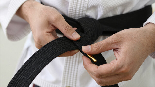 karate gold tip black belt being tied by martial artist