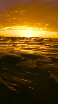 Time lapse video of sunrise over the ocean at Bronte Beach, Sydney, Australia, with glowing red and orange clouds reflected across a gently rippling sea surface.