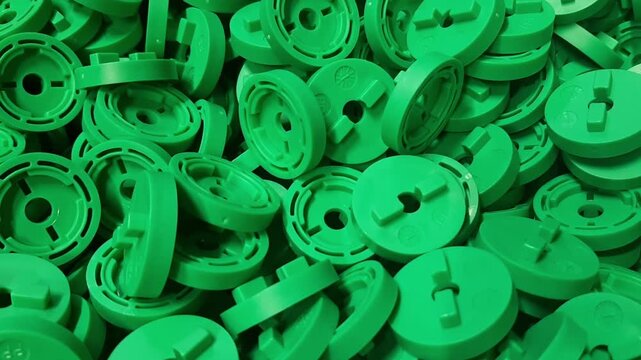 Industrial video of green plastic components moving on factory conveyor belt. Abstract background of manufactured polymer molding details and engineering items.