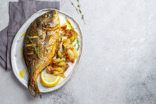 Grilled sea bream or dorada on gray plate. Gray background