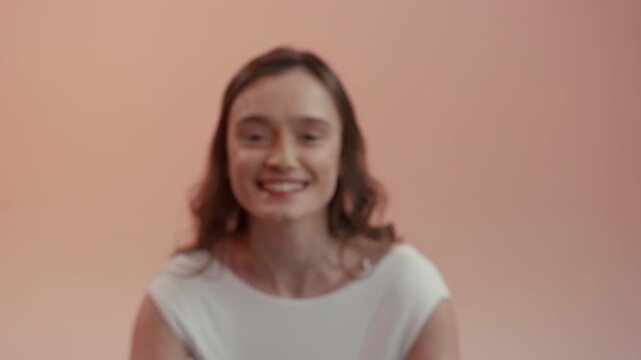 A young woman with brown hair looks directly into the camera with a calm expression and a discreet smile. 4K.