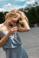 Naklejka premium Woman enjoys a drink outdoors while playing with her hair in a sunny location