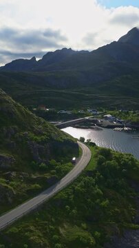 Aerial view of winding road through Lofoten mountains with coastal vil