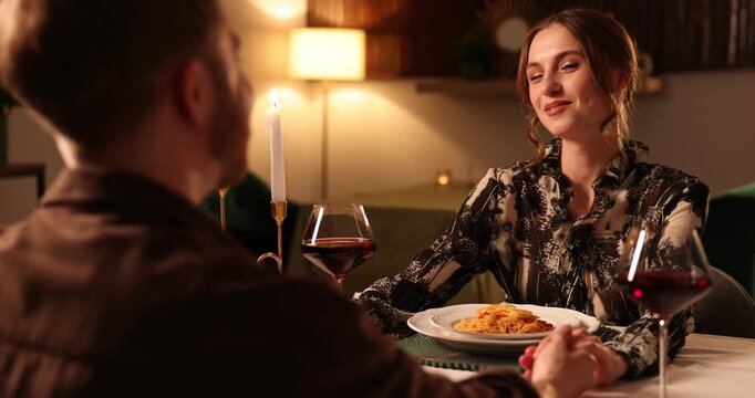 Date. Couple holding hands together at table during romantic dinner in restaurant