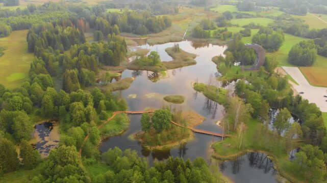 aerial drone shot captures the unique landscape of the Kirkilai lakes in Northern Lithuania. The footage shows the numerous water filled karst sinkholes and the architecturally distinctive, moon-shape