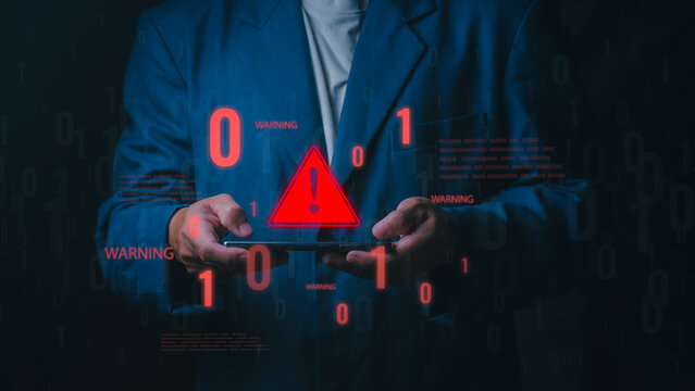 A professional man holds a smartphone displaying a red glowing warning triangle and binary code. This represents a cyber attack, security breach, and system error alert.