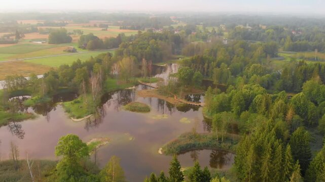 aerial footage of the distinctive landscape of Kirkilai lakes, featuring numerous small, water filled karstic sinkholes surrounded by lush green forests and fields in the Biržai Regional Park, Lithuan