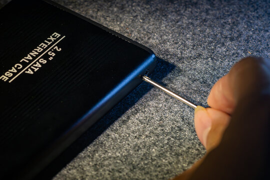 Close up of a hand using a precision screwdriver to assemble a black two point five inch SATA external hard drive case