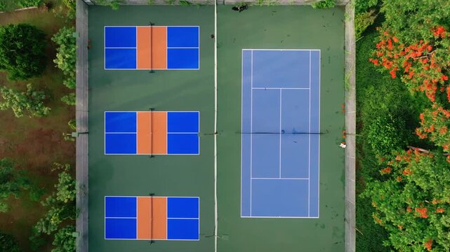Outdoor Pickleball Courts. Sweeping views in motion of empty pickleball courts. Moving forward across several courts in a row. Public city park setting with cloudy blue Summer sky.