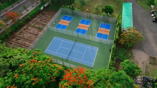 Outdoor Pickleball Courts. Sweeping views in motion of empty pickleball courts. Moving forward across several courts in a row. Public city park setting with cloudy blue Summer sky.