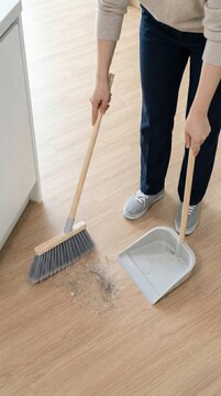 A woman sweeping the floor with a broom in her new house