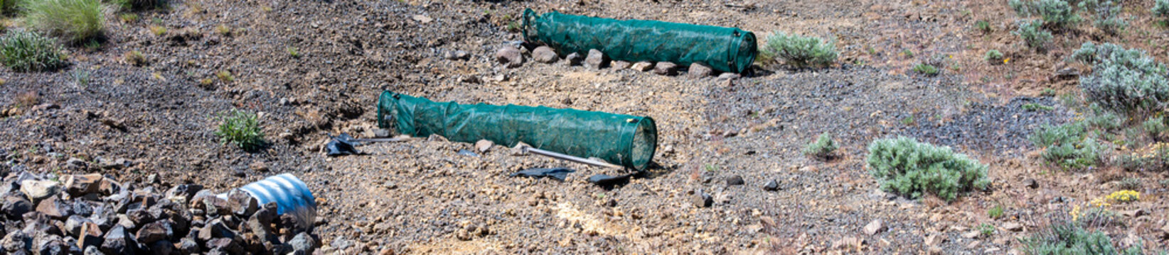 Dry slope erosion control with green mesh covered Spring Berm tubes placed below metal stormwater outflow pipe, shrub-steppe environment
