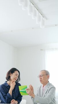 通帳を見てお金をねだる女性とシニア男性