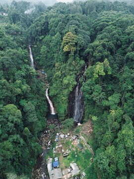 Beautiful aerial drone view of Curug Cigamea, a famous twin waterfall nestled inside a lush green tropical forest and valley in Bogor, West Java, Indonesia