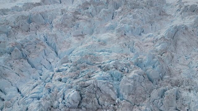 Aerial view of the massive Ilulissat glacier with deep blue crevasses and jagged ice formations in Ilulissat, Avannaata, Greenland.