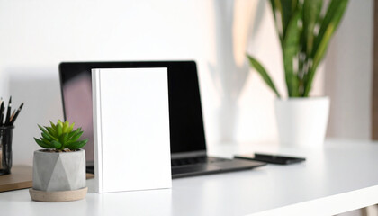 Fototapeta premium Clean Workspace Mockup: A minimalist desk setup featuring a blank book, laptop, and potted plants, bathed in natural light, ideal for showcasing designs or study materials.