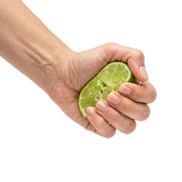 Hand squeezing fresh lime half, extracting juice, isolated on white background