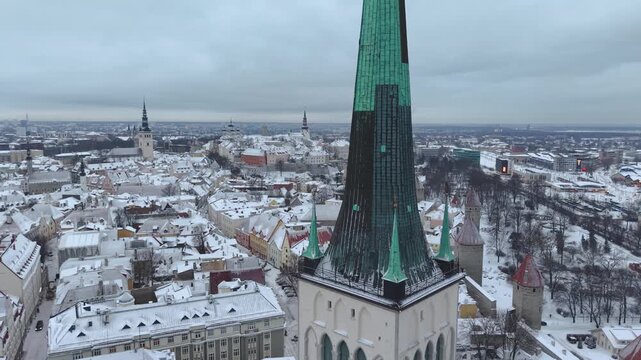 Aerial view of the historic St. Olaf's Church spire rising above the snow-covered rooftops of the old town in Tallinn, Harju County, Estonia.