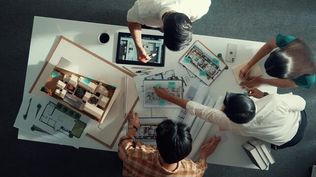 Top down aerial view of architect engineer team writing sticky notes and sticking note at house model while interior designer talking and discussing about building exterior designing. Alimentation.