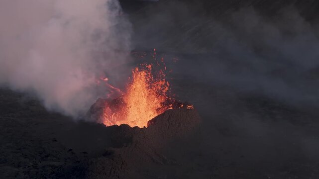 Aerial view of a powerful volcanic eruption with glowing lava fountains and thick volcanic ash plumes rising from the crater in Grimsey, Reykjanesbaer, Iceland.