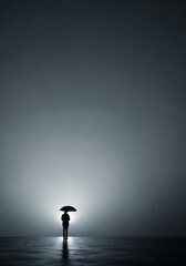 Obraz premium Solitary Person with Umbrella Standing in Foggy Landscape at Night.