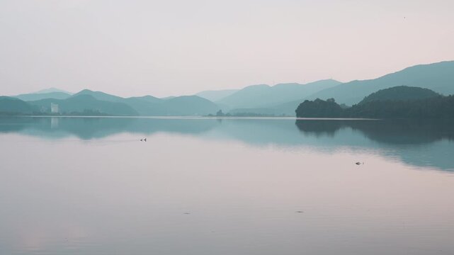 Tranquil wide view of Daecheongho lake with mountain reflections in serene dawn light - 고즈넉한 새벽 빛 아래 푸르스름한 산세와 잔잔한 수면 반사가 평화롭게 어우러진 대청호 전경 풍경
