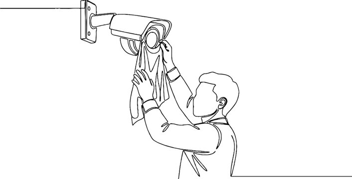 Man installing security camera on wall indoors.