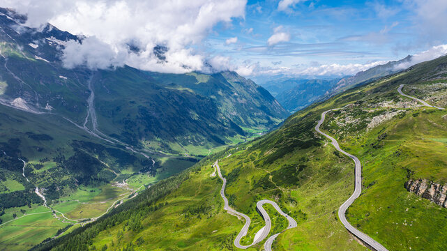 Aerial view of the winding Grossglockner High Alpine Road cutting through the green mountain landscape of the Austrian Alps during a bright and sunny summer day in Austria.
