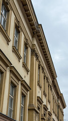 Obraz premium Historic European Building Facade With Classical Columns, Ornate Cornices And Traditional Architecture Against Overcast Sky