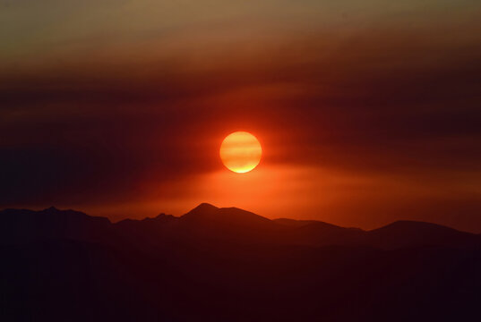 an eerie sunset, with sun spots,  over the colorado rocky mountains through the smoke of the western forest fires , as seen from broomfield