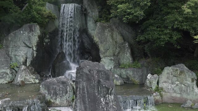 日本庭園に流れる静かな滝と石組の風景
