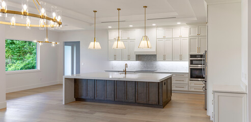 Wide panoramic view of modern luxury kitchen interior with large wooden island shaker cabinets and pendant lights in custom home © Andrei Liashchou