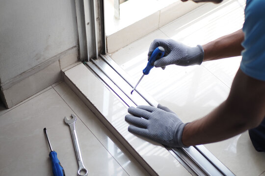 Worker repairs sliding door track in home