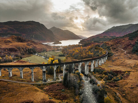 Glenfinnan Viaduct And Curving Railway Over Scottish Highlands Valley With Autumn Lake View