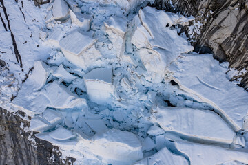 Aerial View of Broken Glacier Ice and Crevasses Against Rocky Cliffs in British Columbia, Canada