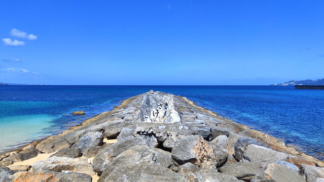 Rocky pier in the sea with a stone on it that says danger ahead.