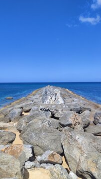 Rocky pier in the sea with a stone on it that says danger ahead.