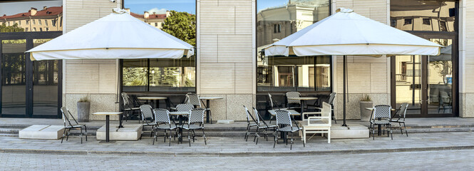 Fototapeta premium outdoor cafe on city street. empty cafe terrace with tables, wicker chairs and umbrellas.