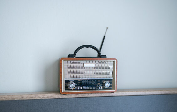 Retro Vintage Portable Radio on Wooden Surface,A vintage-style portable radio with a wooden frame and metal grille sits on a sleek modern surface, blending retro aesthetics with contemporary interior 