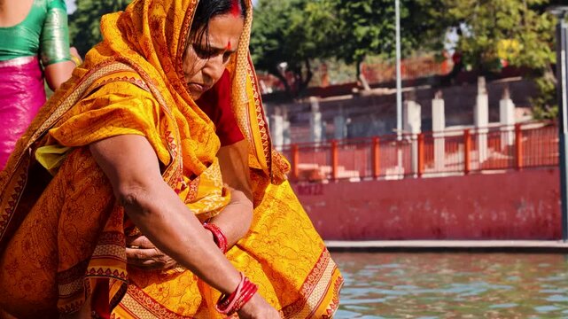 Woman Worshipper Bowing in gauri pujan Prayer During Sacred River Pilgrimage