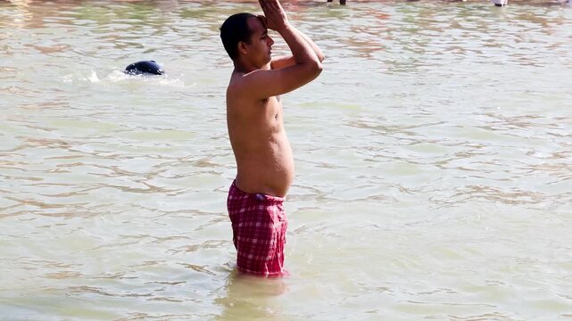 Spiritual Pilgrim Offering Prayers During Holy Dip in Sacred Waters