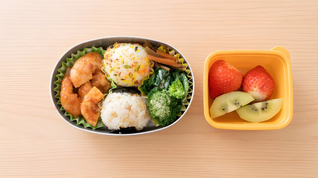 A Japanese homemade bento lunch box with two rice balls (onigiri) - one with furikake and one wrapped in nori seaweed, chili shrimp, broccoli, and a separate yellow container with strawberries and kiw