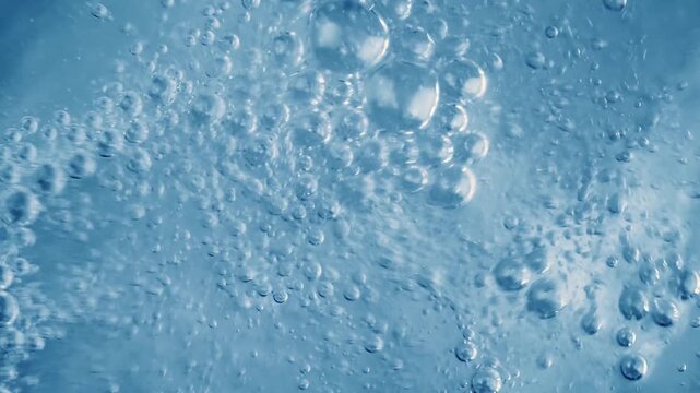 Effervescent tablet dissolving in water creating blue bubbles and fizzing motion.