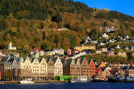 Panorama of Bergen Port with hanseatic buildings of World Heritage Site Bryggen, boats and mountain Fl&oslash;yen with funicular railway Fl&oslash;ibanen in autumn in Norway