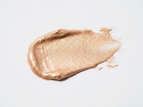 A smear of shimmering gold cosmetic cream or highlighter isolated on white background
