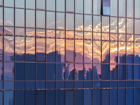 Modern skyscraper windows capturing a reflection of a sunset city.